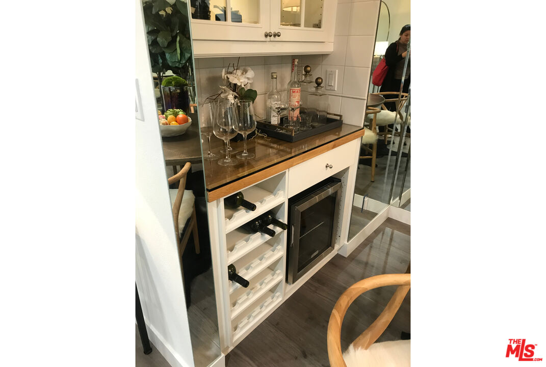 Wine bar with glassware, open bottle storage, and a built-in wine refrigerator.