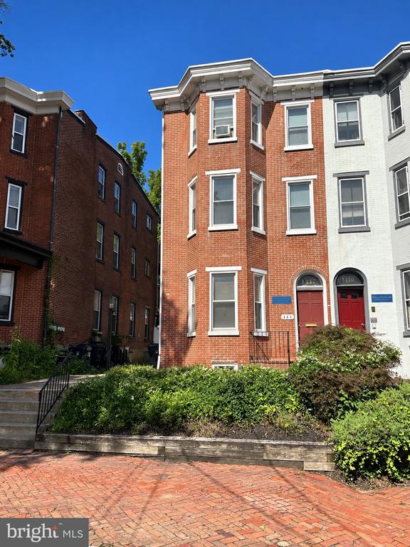 Attached brick homes with arched red doors, landscaped front beds, and a brick-paved walkway.