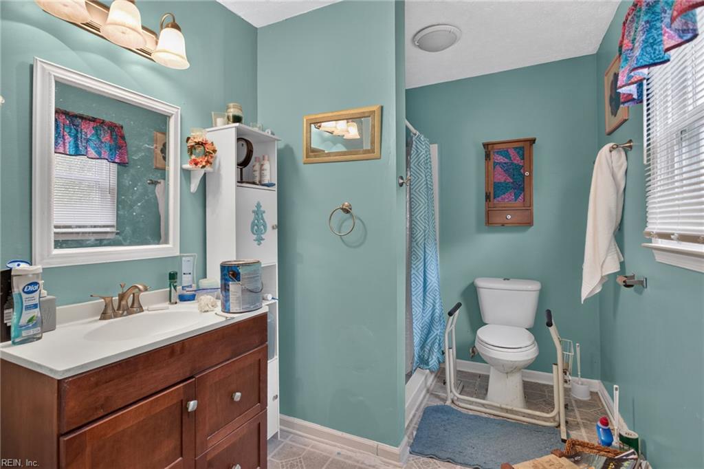 Bathroom with teal walls, a dark wood vanity, and a blue patterned shower curtain.