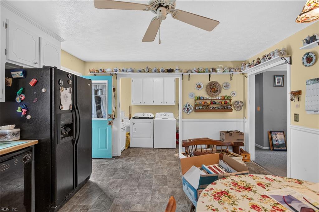 Kitchen and laundry area with a black refrigerator, washer and dryer, and decorative pottery displayed on shelves.