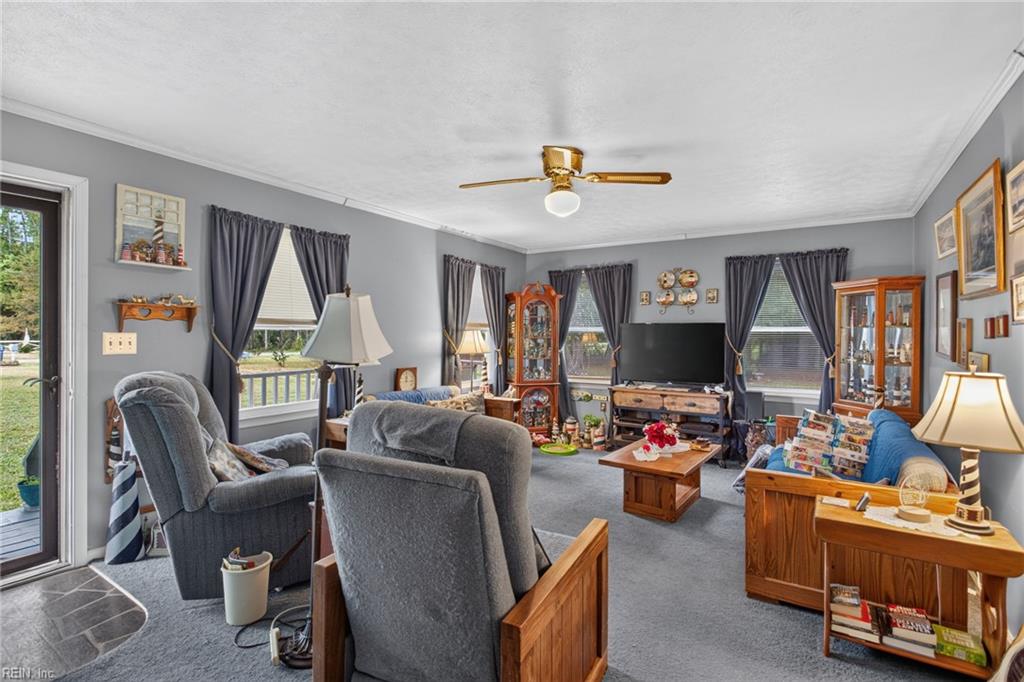 Furnished living room with gray recliners, dark curtains, wooden display cabinets, and a television.