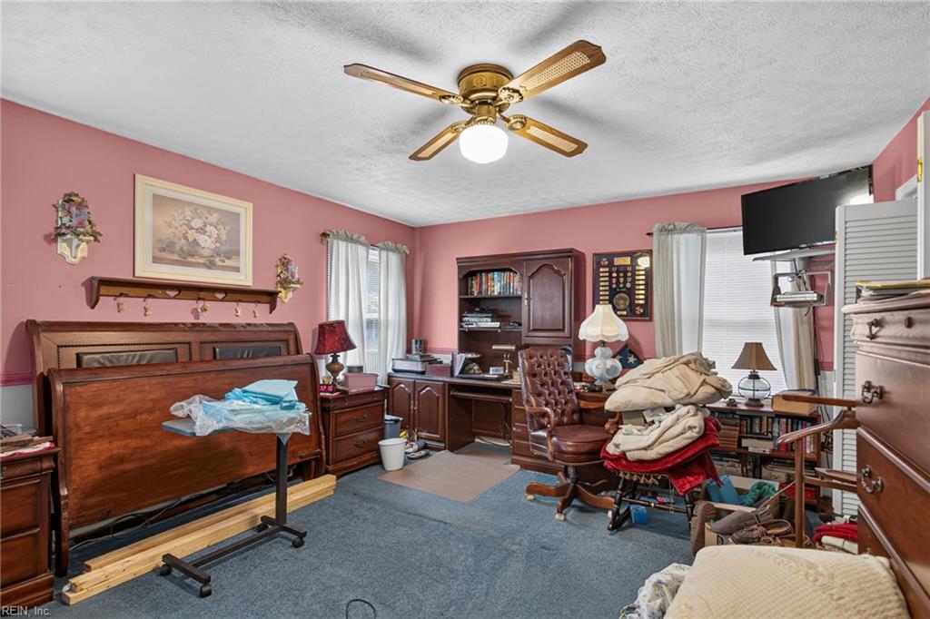 Bedroom with pink walls, a large wooden bed, matching furniture, and a ceiling fan.