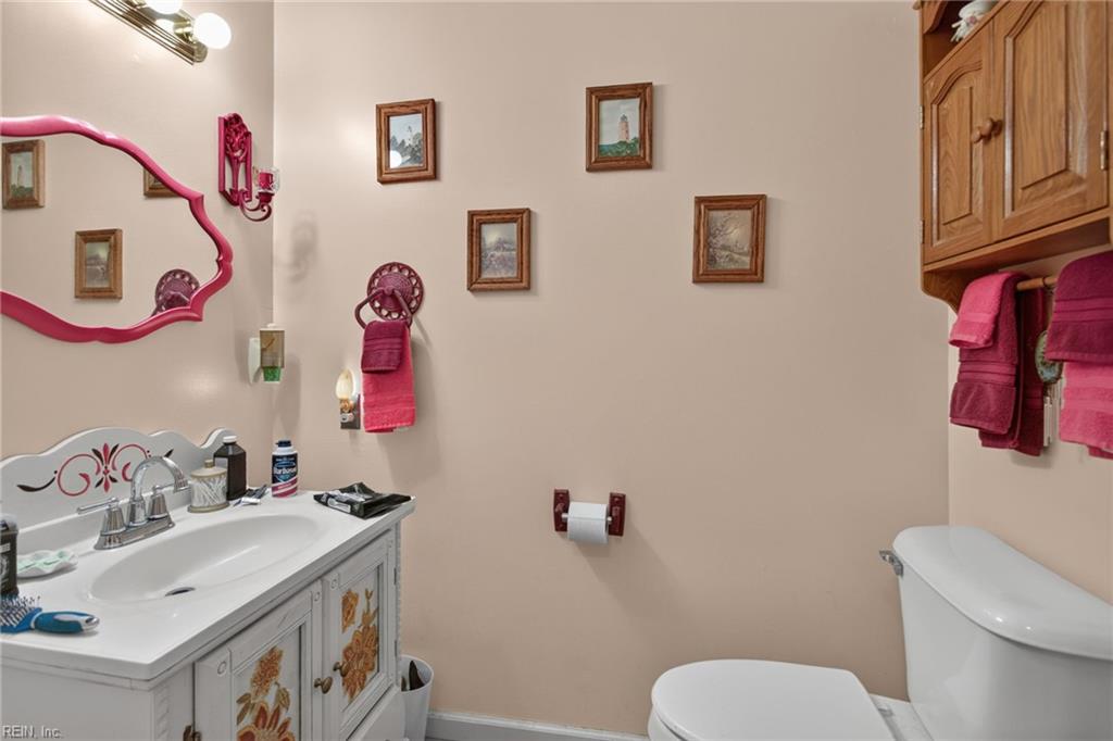 Bathroom with floral-panel vanity, pink-framed mirror, matching towels, and framed wall art.