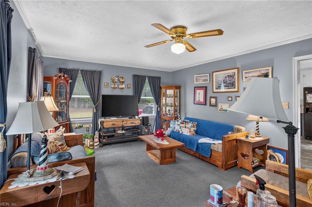 Furnished living room with a blue sofa, gray carpet, wooden furniture, and a ceiling fan.