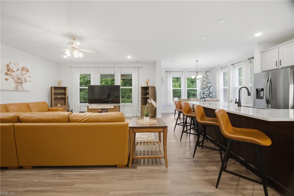 Open-plan living room and kitchen with a leather sectional, island bar stools, and a decorated Christmas tree.