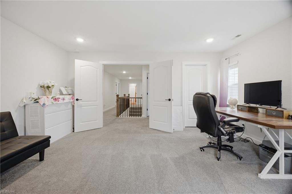 Furnished upstairs office with a desk and monitor beside open double doors to the hallway.