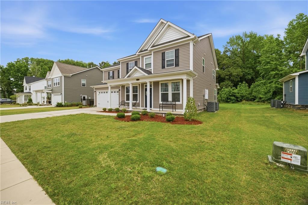 Two-story beige home with a covered porch, attached garage, and broad front lawn.