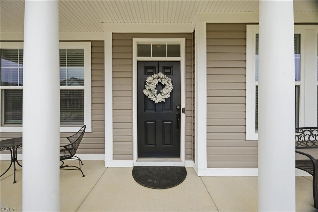 Home’s front entrance with a black door, white wreath, and covered porch with white columns.
