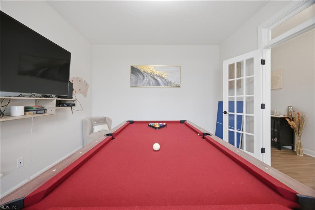 Game room with a red-felt pool table, wall-mounted television, and open French doors.