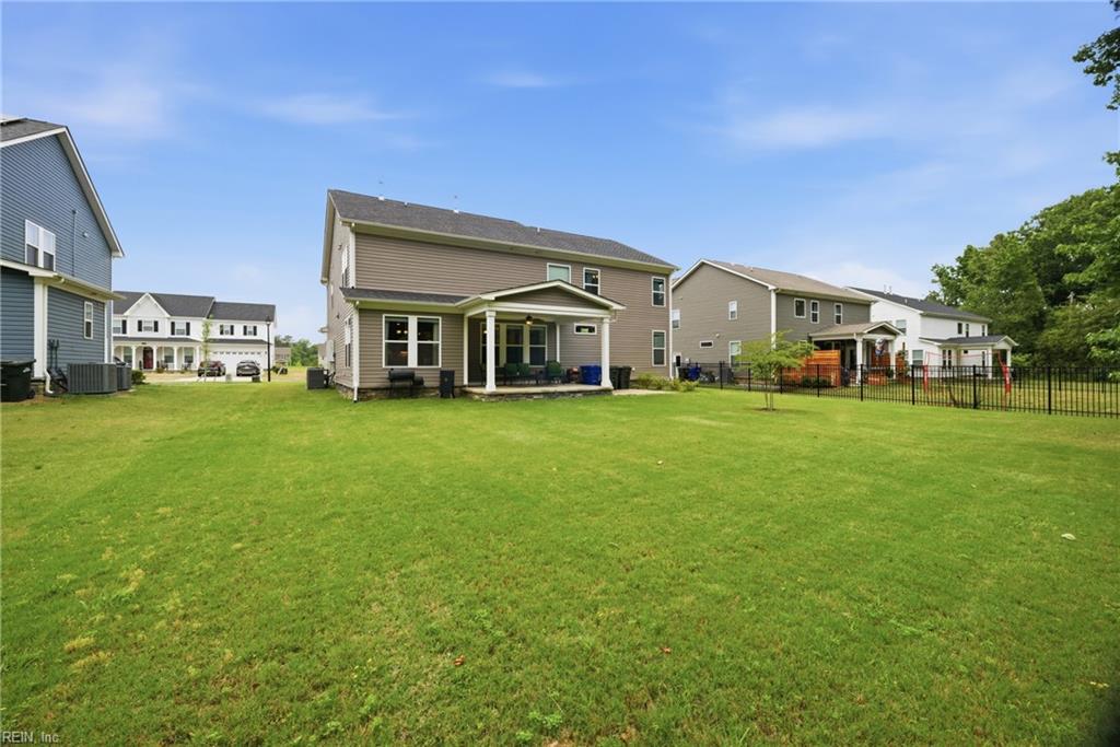 Two-story gray home with a covered patio and broad lawn, viewed from the backyard.