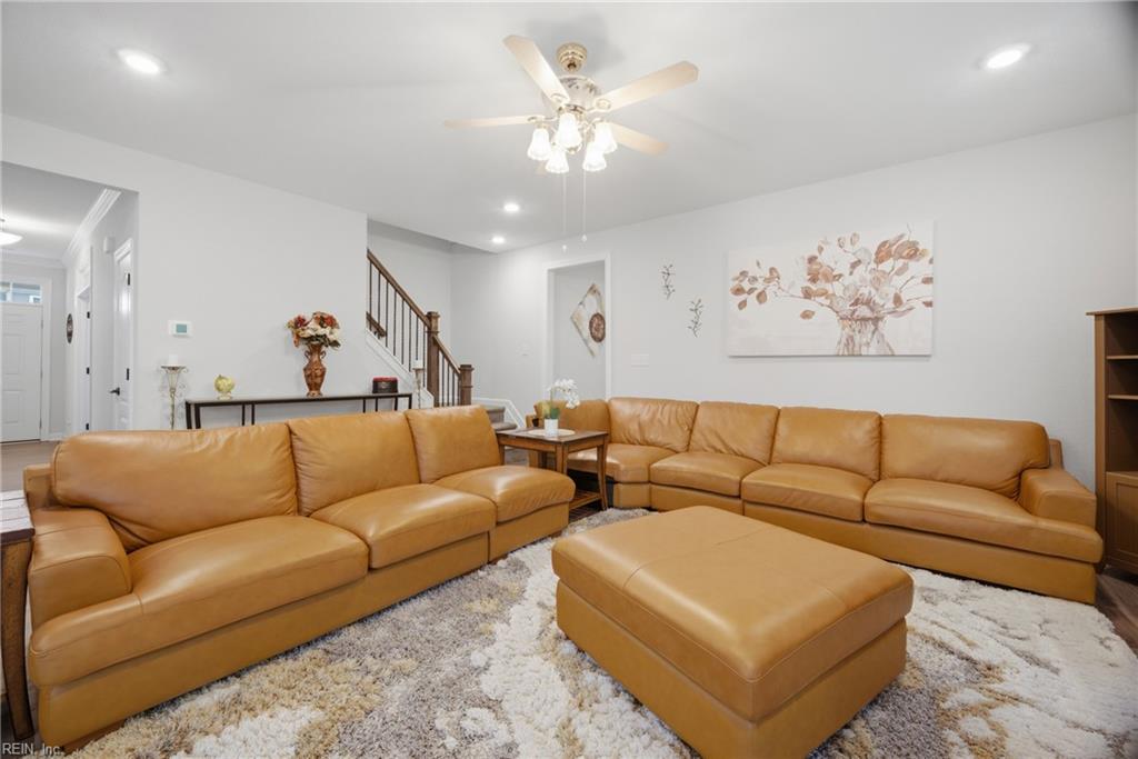 Living room with a tan leather sectional, matching ottoman, and staircase in the background.