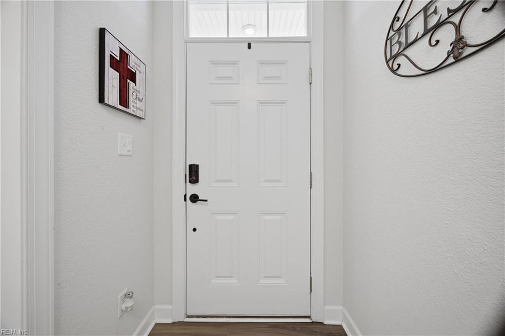 Entryway with a white paneled front door, transom window, and dark hardware.