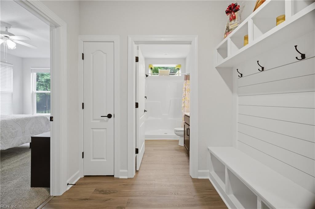 Mudroom with a built-in white bench, coat hooks, cubbies, and light wood flooring.