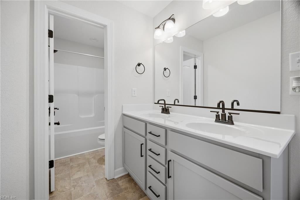 Bathroom with a white double-sink vanity and adjoining tub and shower.