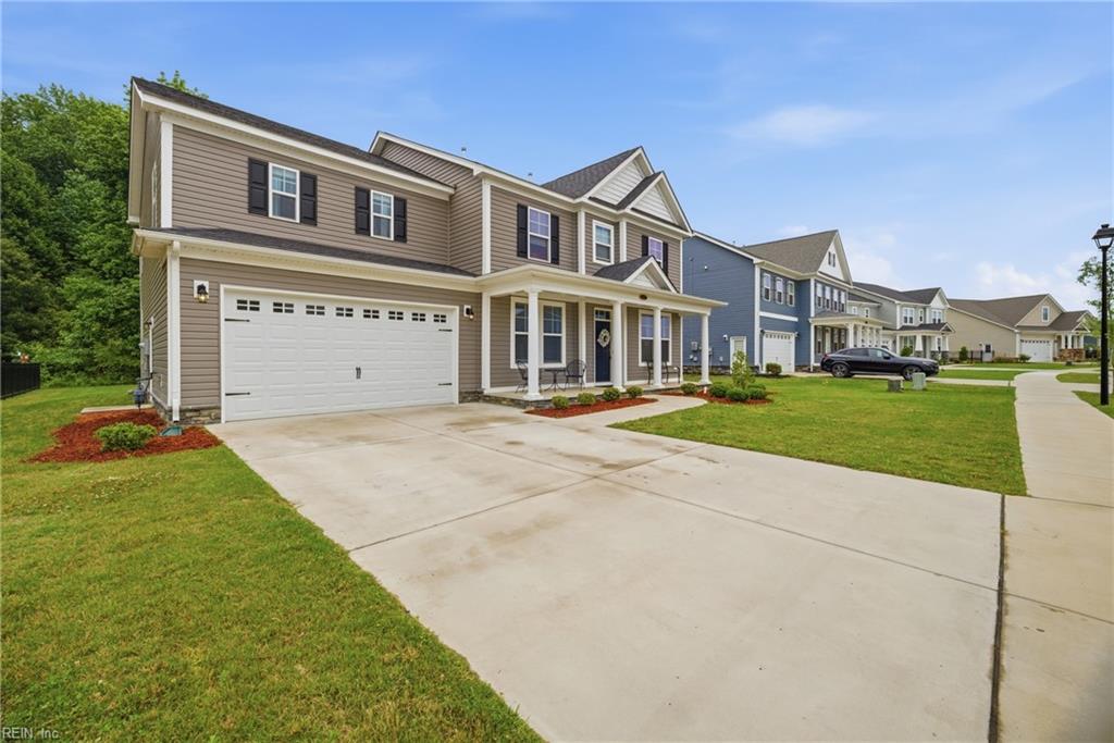 Two-story taupe house with a double garage, wide driveway, and neighboring homes along the street.