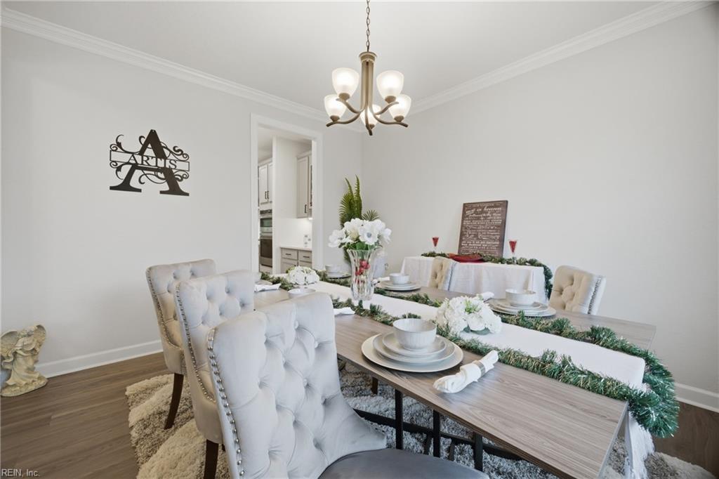 Staged dining room with a long table, white tufted chairs, floral arrangements, and green garland.