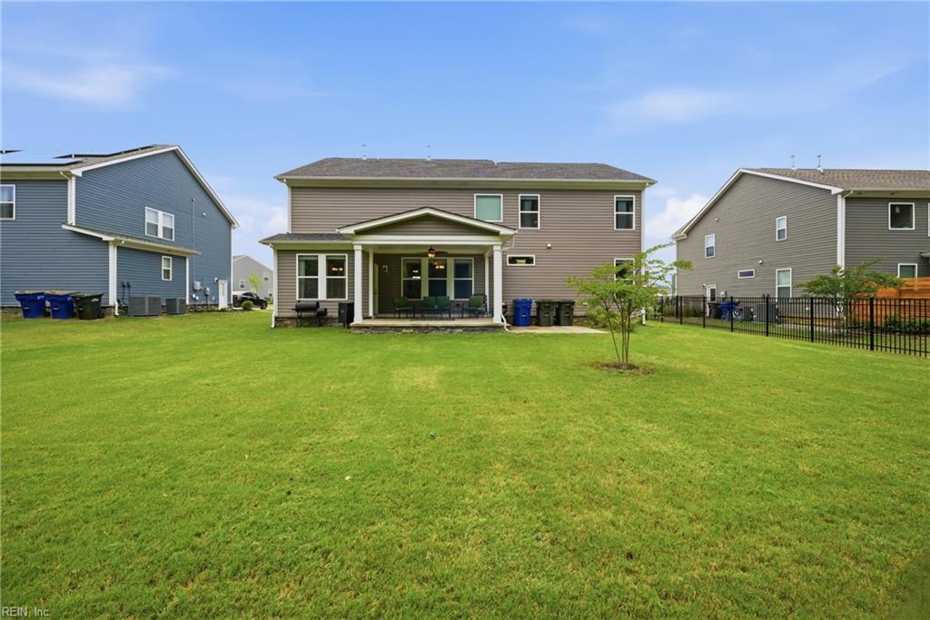 Rear exterior of a two-story home with a covered patio and broad green lawn.
