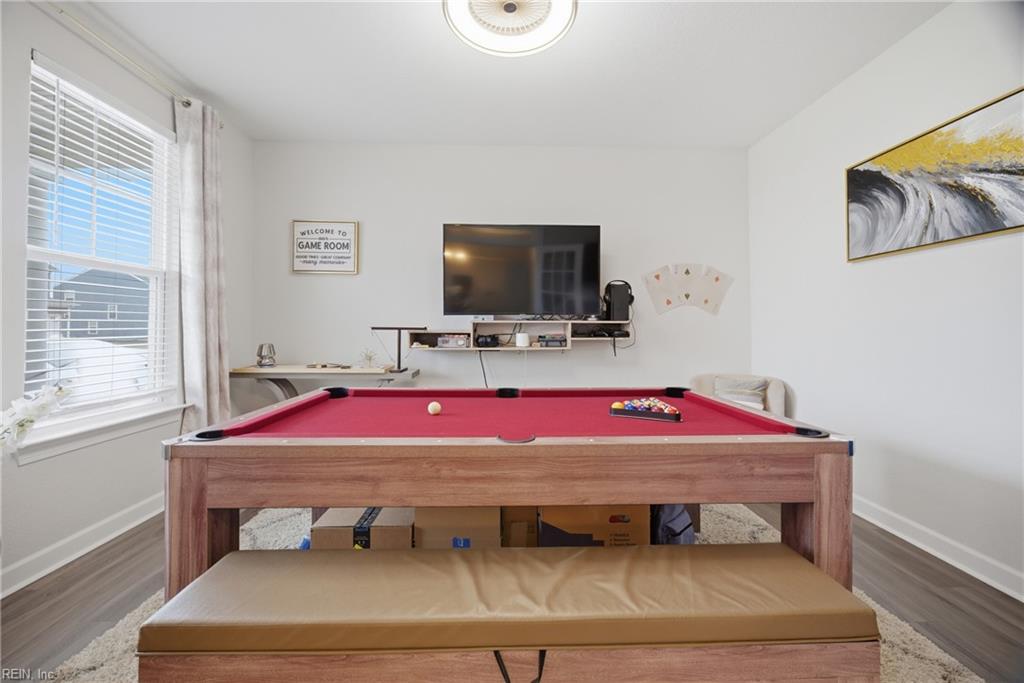 Game room with a red-felt pool table, wall-mounted television, and window with blinds.