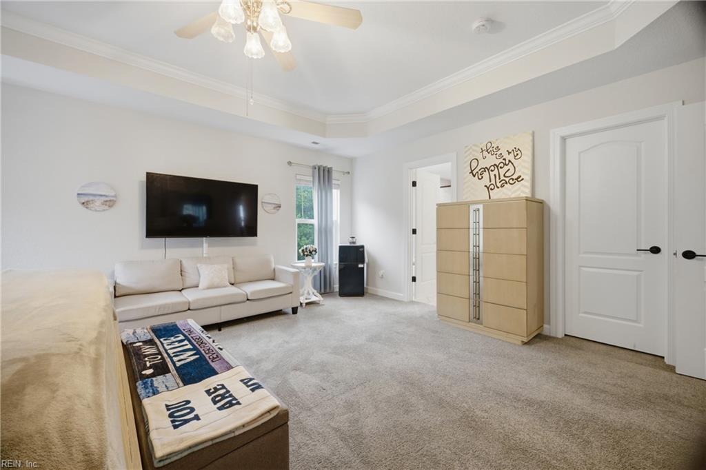 Living room with a sectional sofa, wall-mounted TV, beige carpet, and light-wood cabinet.