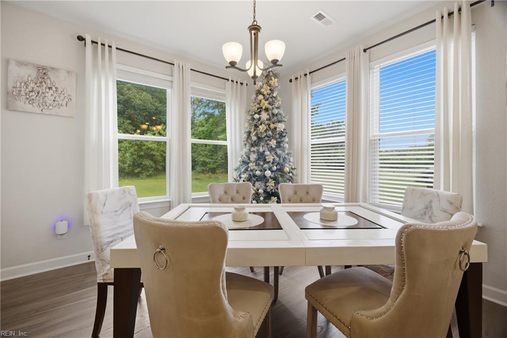 Dining room with an elegant table, tall windows, and a decorated Christmas tree.
