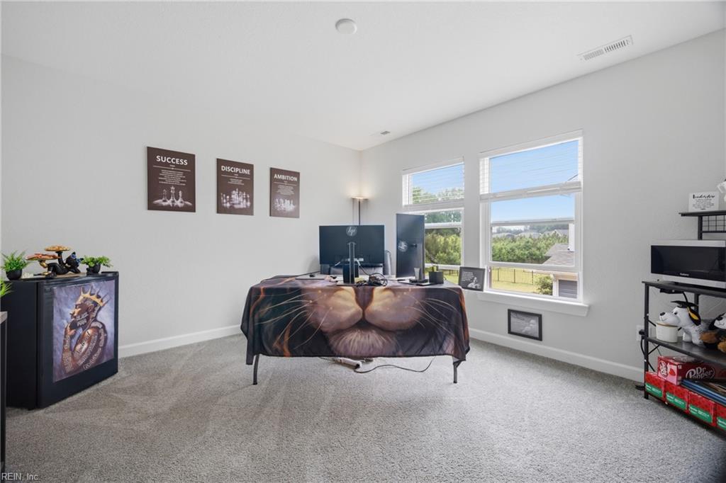 Home office with a multi-monitor desk, motivational posters, and windows overlooking a fenced yard.