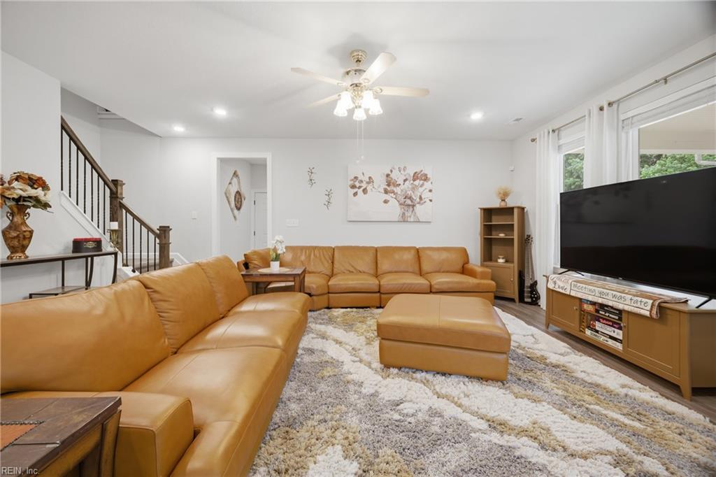 Living room with a tan leather sectional, matching ottoman, and staircase