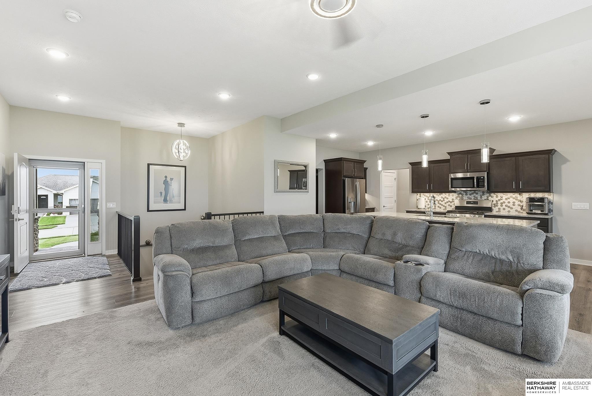 Open-plan living room with a large gray sectional facing a dark coffee table and kitchen.