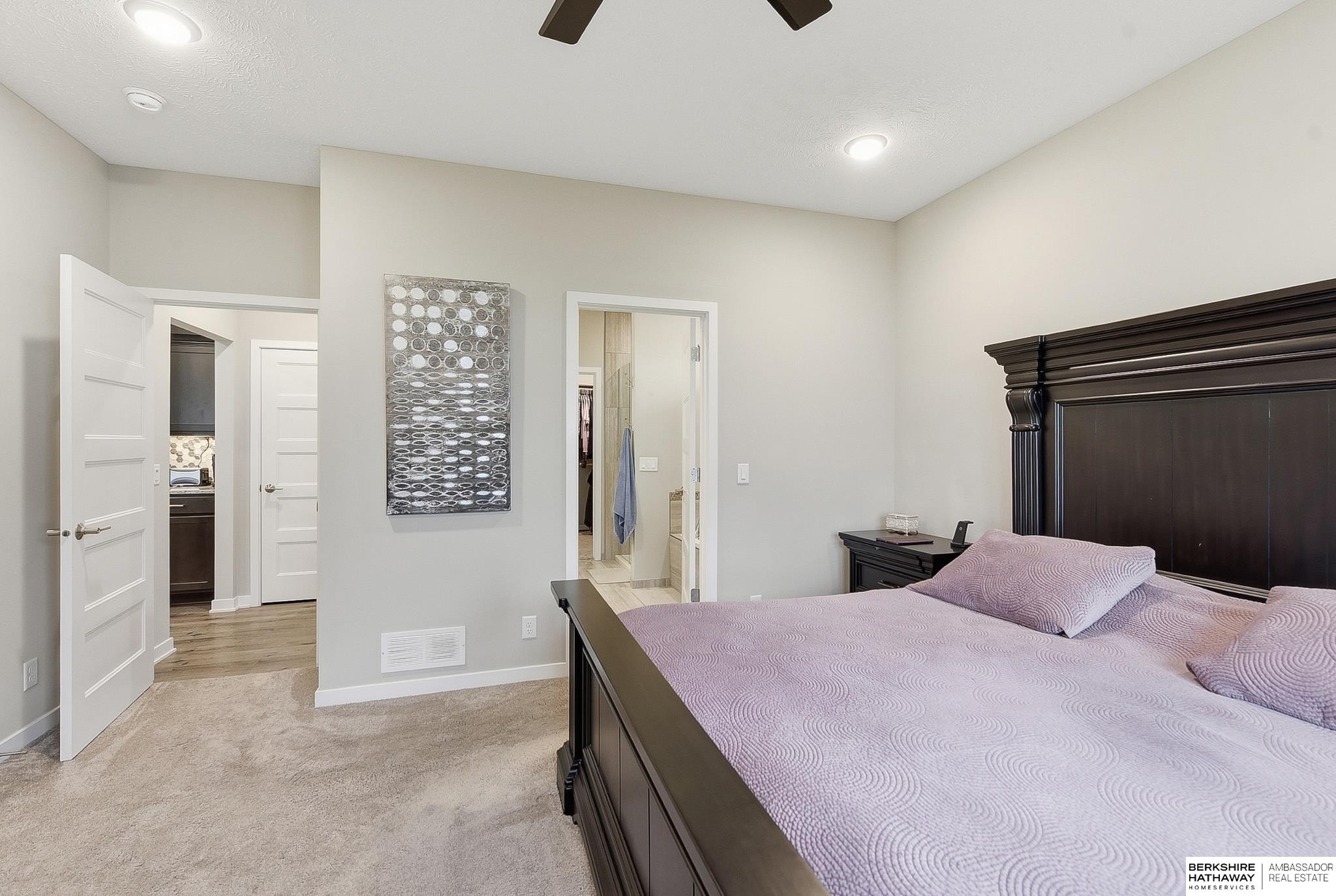 Bedroom with a dark wood bed, lavender bedding, and open doorways to an adjoining bathroom and closet.