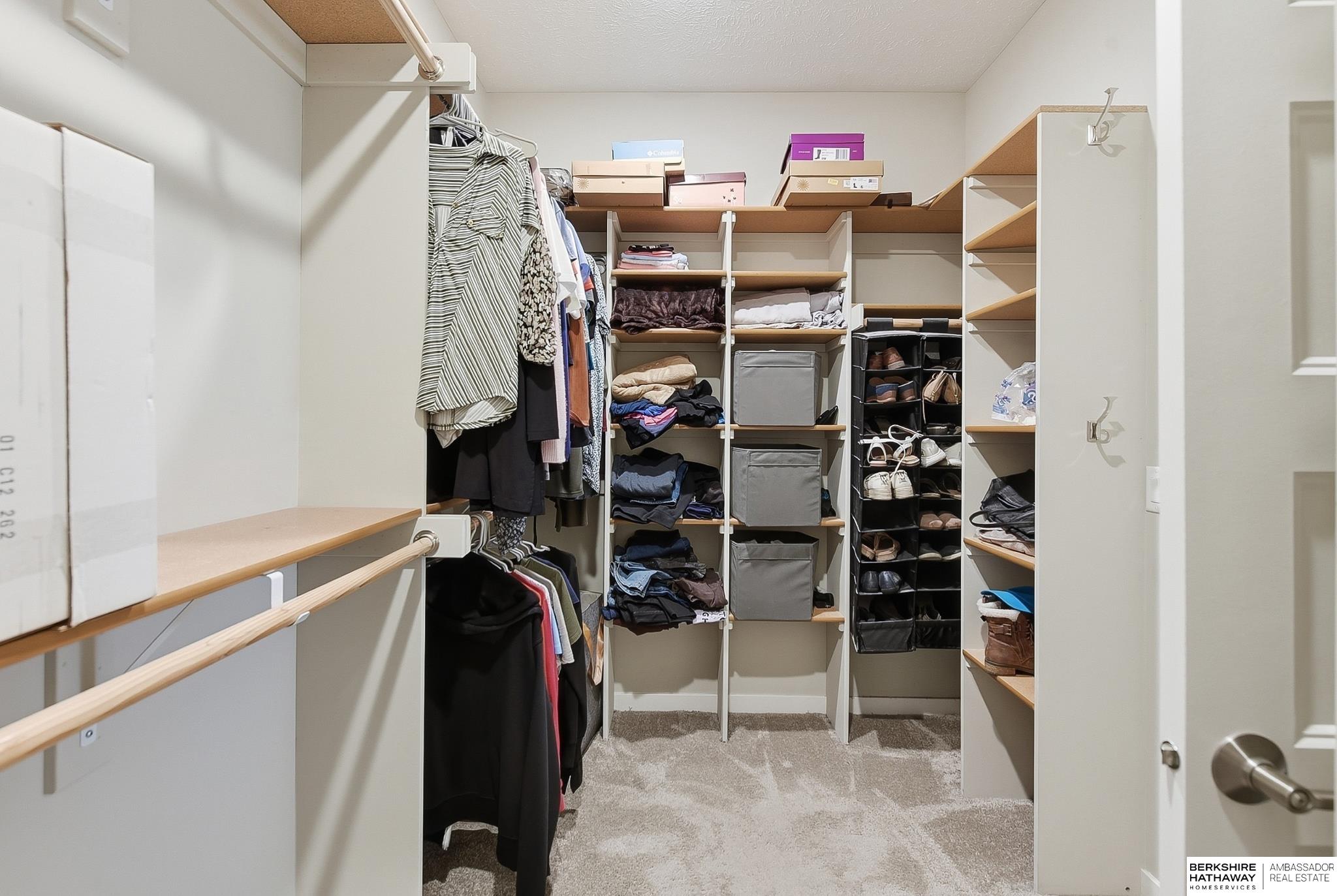 Walk-in closet with built-in shelving, hanging clothes, storage bins, and shoe racks.