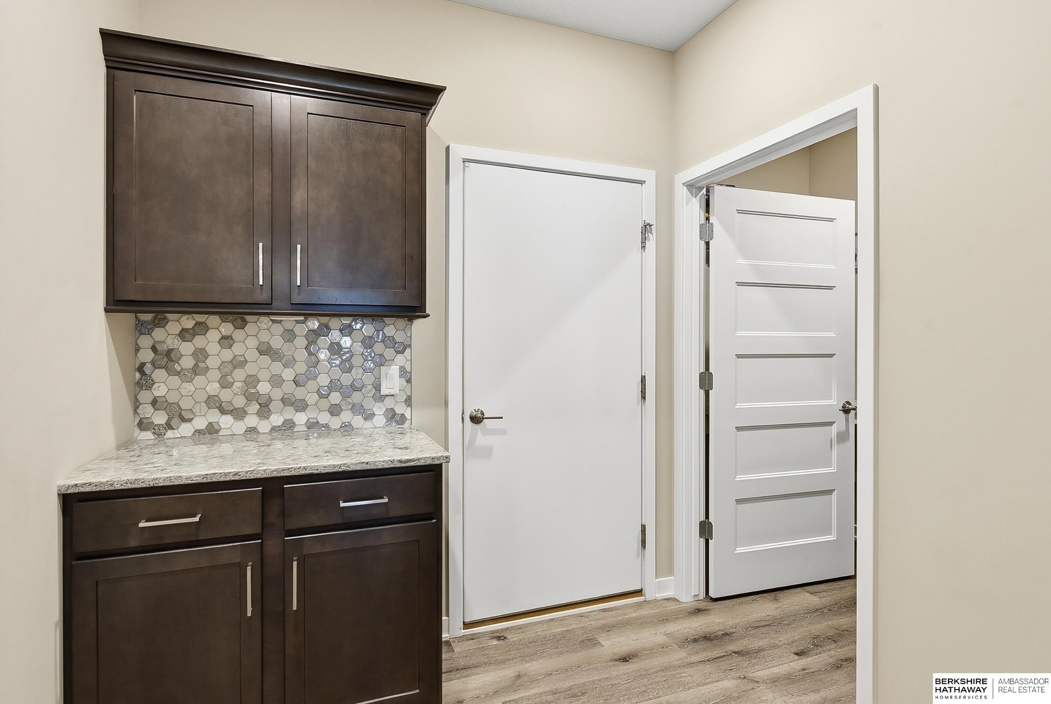 Entryway with dark built-in cabinets, a hexagonal tile backsplash, and two white doors.