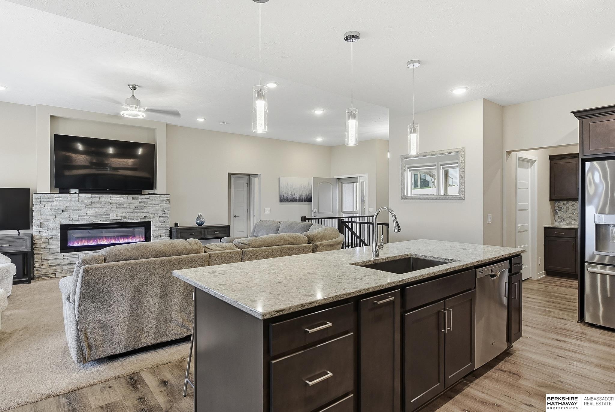 Open kitchen and living room with a granite island and stone fireplace.