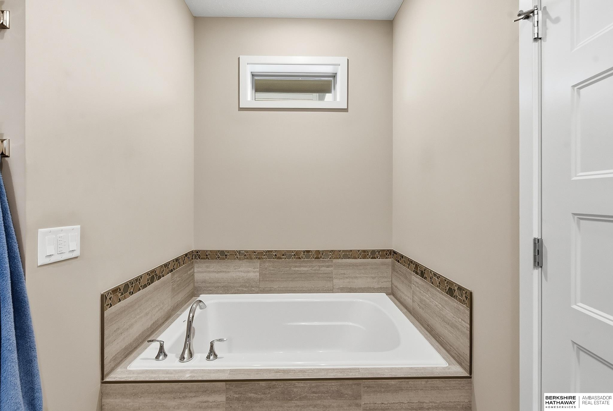 Built-in bathtub with chrome fixtures, tiled surround, and a small horizontal window above.