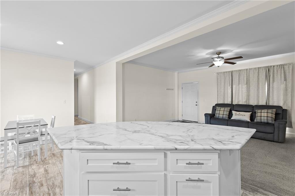 Open-plan kitchen and living room with a large white island, dining table, and gray sofa.