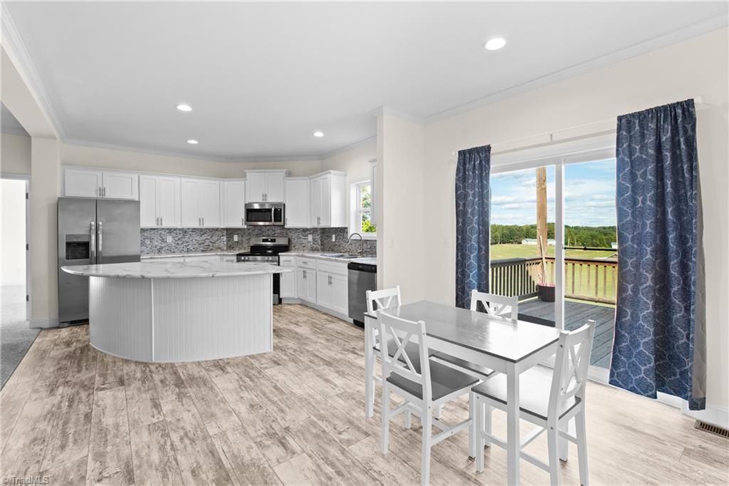 Open kitchen and dining area with a curved island and sliding doors to a deck.