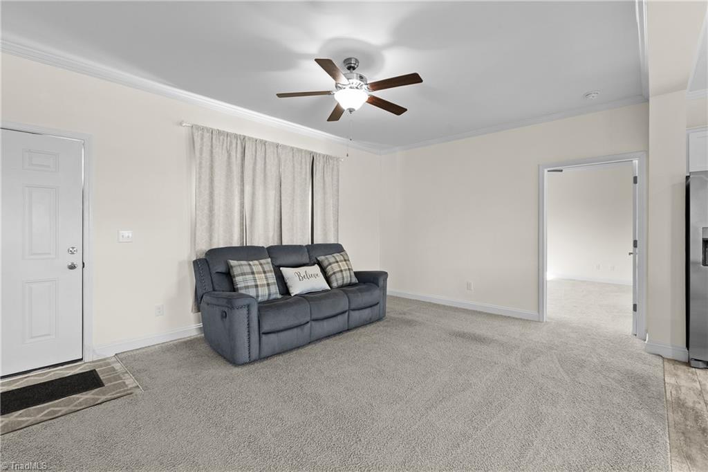 Living room with a dark gray sofa, curtained windows, and a ceiling fan.