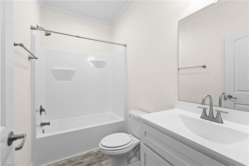 Bathroom with a tub-shower combination, white vanity, large mirror, and wood-look flooring.