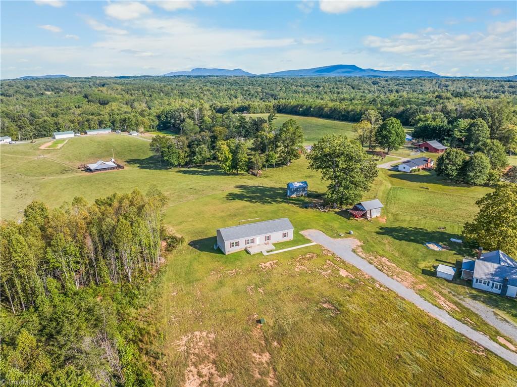 Rural home on open acreage, with outbuildings and distant mountains.