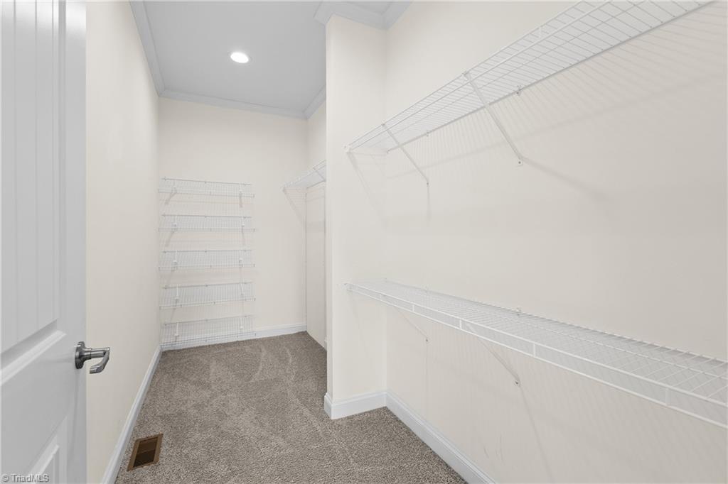Walk-in closet with white wire shelving and beige carpet.