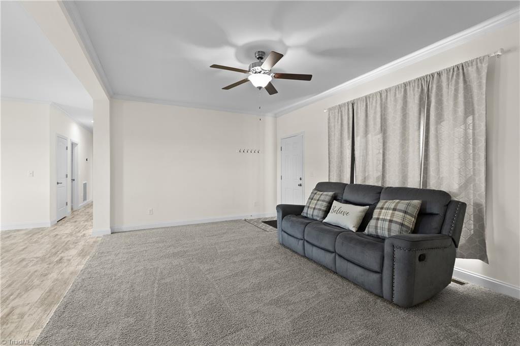 Living room with a gray reclining sofa, patterned curtains, and a ceiling fan.