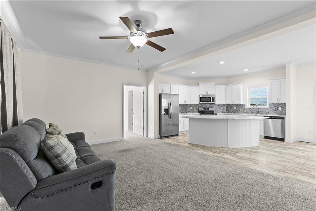 Open living room and kitchen with a gray sofa, white cabinets, and a central island.