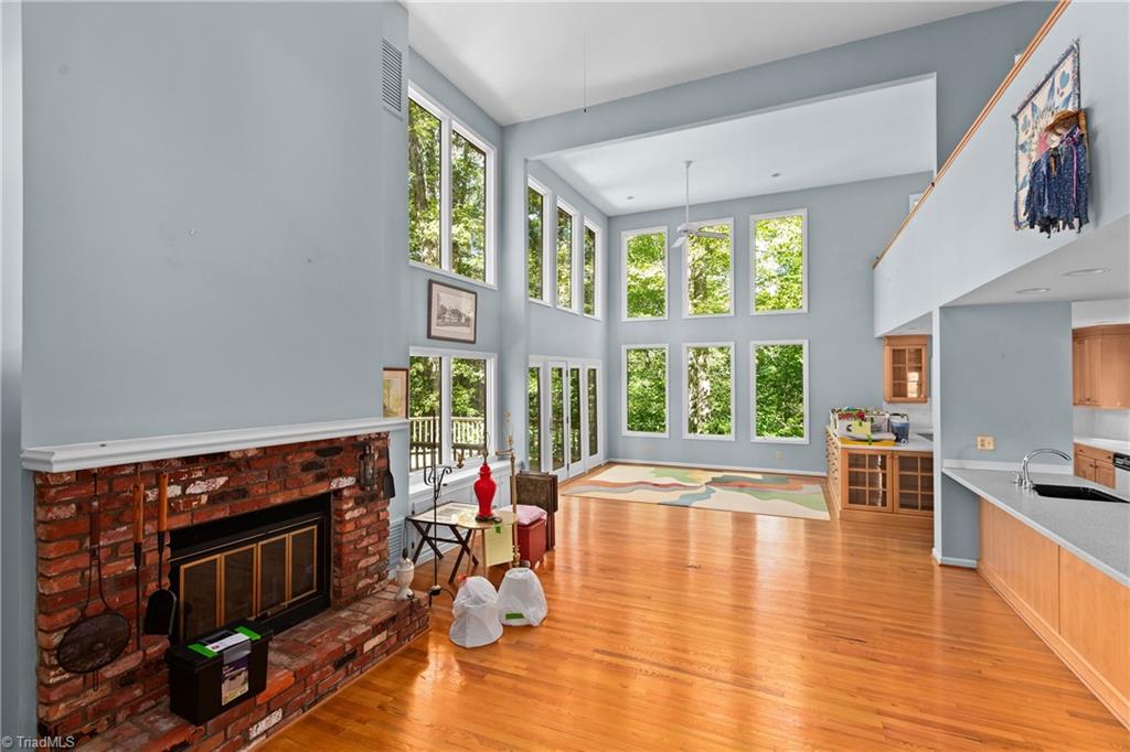 Living area with tall windows, hardwood floors, and a large brick fireplace.