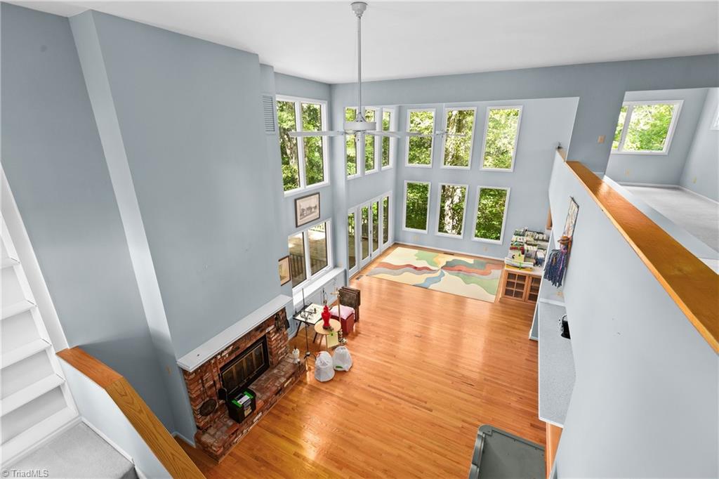 Two-story living room with a brick fireplace, hardwood floors, and tall windows.