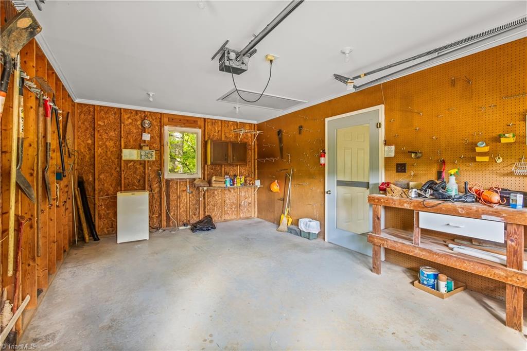 Garage with exposed wood walls, pegboard tool storage, and a workbench.