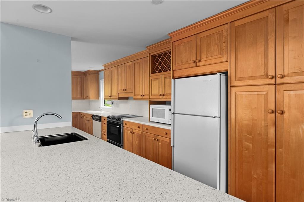 Kitchen with honey-colored cabinets, a speckled countertop peninsula, and stainless-steel appliances.