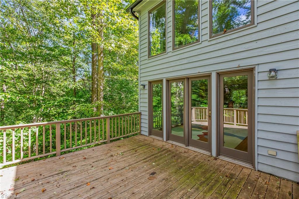 Wooden rear deck with sliding glass doors overlooking a wooded yard.