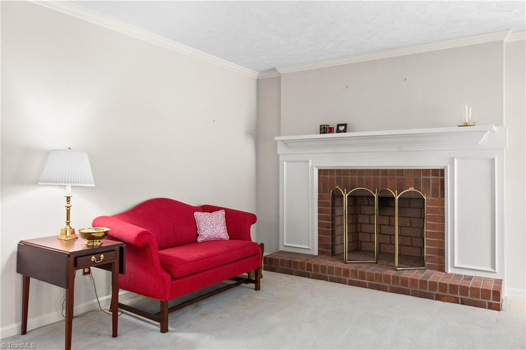 Living room with a red loveseat beside a brick fireplace and white mantel.