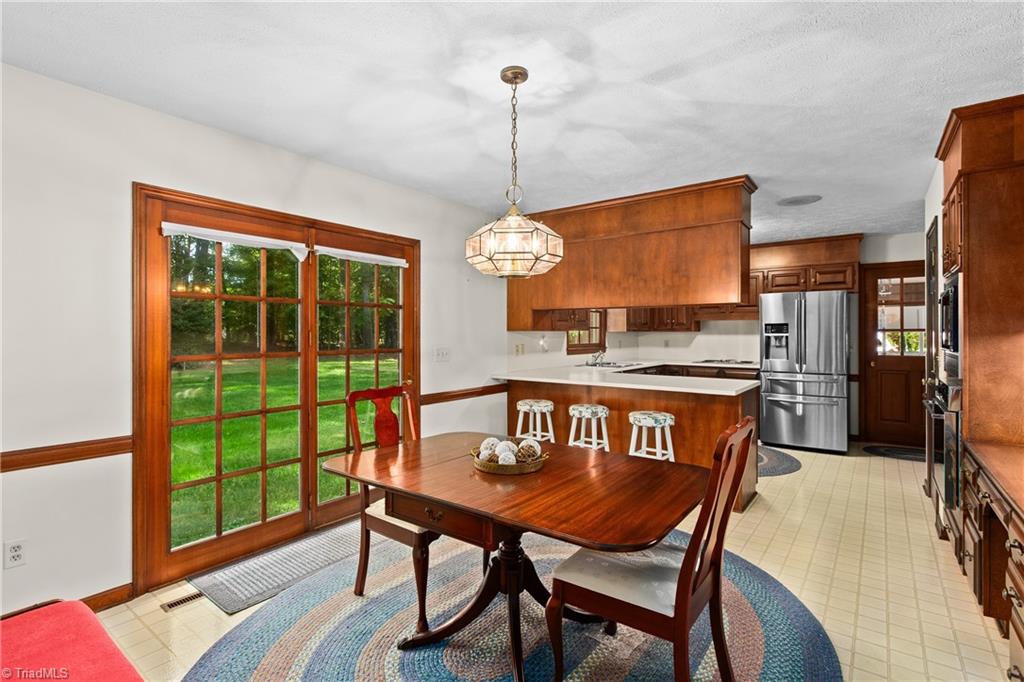Kitchen and dining area with wood cabinetry, a white peninsula, and sliding glass doors overlooking a lawn.