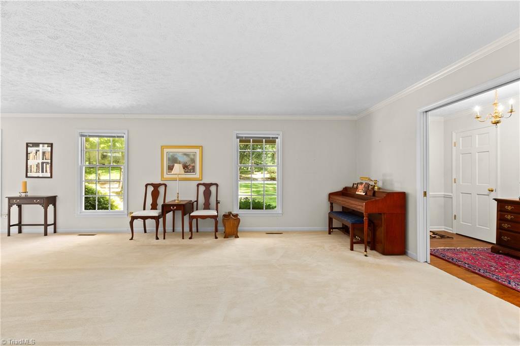 Carpeted room with two windows, antique chairs and table, and a wooden piano.