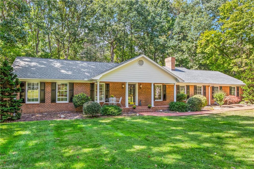 Brick ranch home with a covered front entry, broad lawn, and mature trees.