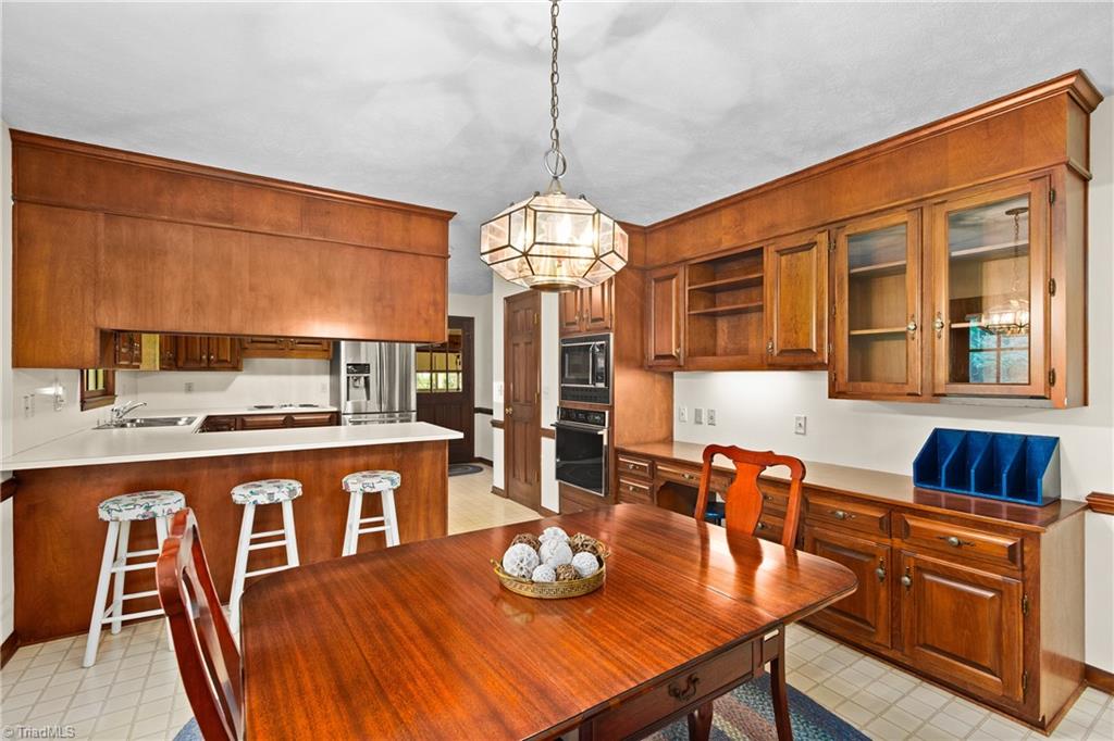 Kitchen and dining area with warm wood cabinetry, a breakfast bar, and a large wooden table.